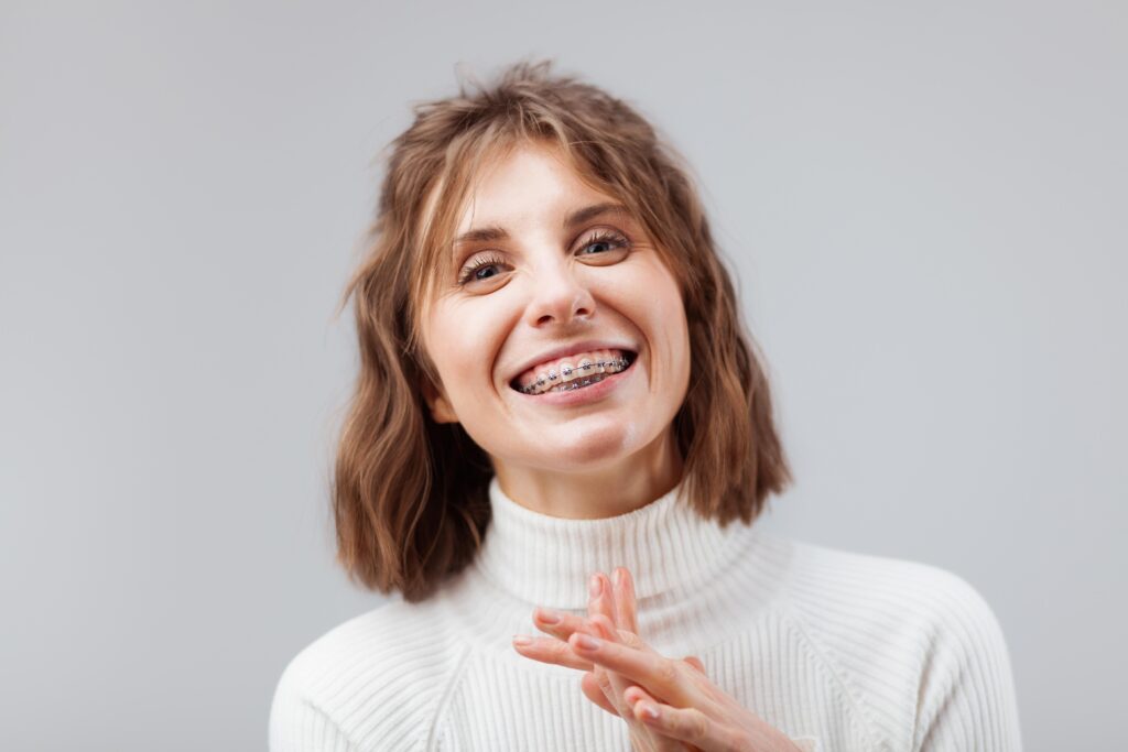 Woman in white shirt smiling with braces